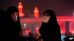 Shii'te Muslim worshippers wearing protective face masks to help prevent spread of the coronavirus light candles outside the shrine of Imam Hussein during the festival of Ashoura in Karbala, Iraq, Aug. 30, 2020.