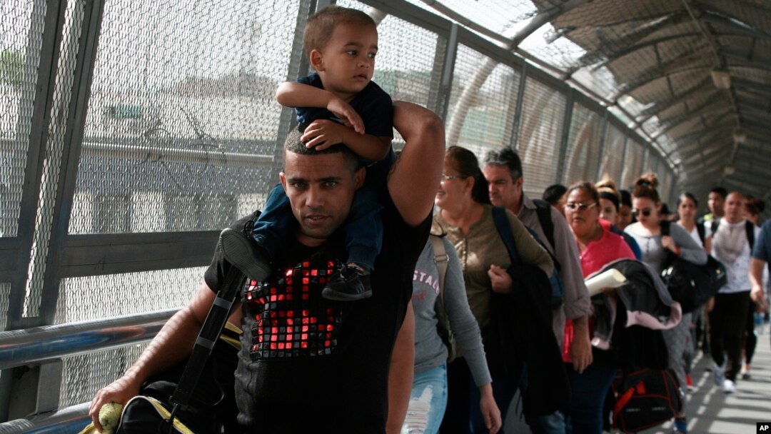 Para migran asal Kuba dikawal oleh para pegawai imigrasi di Ciudad Juarez, Meksiko, saat mereka menyeberangi jembatan internasional Paso del Norte untuk diproses sebagai pencari suaka di sisi perbatasan wilayah AS, 29 April 2019.
