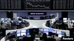 FILE - Traders work at their desks in front of the German share price index, DAX board, at the stock exchange in Frankfurt, Germany, Feb. 16, 2016. 