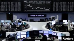 Traders work at their desks in front of the German share price index, DAX board, at the stock exchange in Frankfurt, Germany, Feb. 16, 2016. 