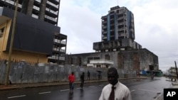 People walk past buildings damaged or unfinished as a result of Liberia's decade-and-a-half long civil war. In the post-war era, health officials are stepping up the fight against leprosy.