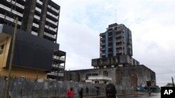 People walk past buildings damaged or unfinished as a result of Liberia's decade-and-a-half long civil war. In the post-war era, health officials are stepping up the fight against leprosy.