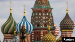 FILE - A woman walks in Red Square with the domes of St. Basil's Cathedral in the background in Moscow, May 16, 2024.