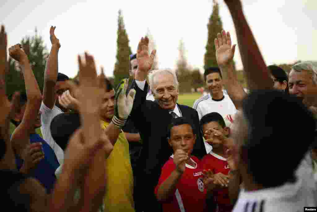 Former Israeli president Shimon Peres is seen with Israeli and Palestinian children during an event to begin a year of training in an Israeli-Palestinian soccer program, launched by the Peres Center for Peace, in Kibbutz Dorot, outside the Gaza Strip, Sept. 1, 2014.