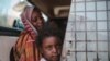 FILE - In this file picture taken Tuesday, April 14, 2015, a Sudanese girl looks out of the window while waiting with her mother in a public bus in Izba, an impoverished neighborhood on the outskirts of Khartoum, Sudan. Forty percent of children…
