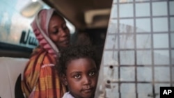 FILE - In this file picture taken Tuesday, April 14, 2015, a Sudanese girl looks out of the window while waiting with her mother in a public bus in Izba, an impoverished neighborhood on the outskirts of Khartoum, Sudan. Forty percent of children…