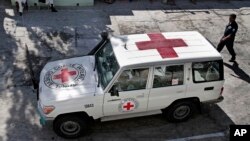 FILE - An Afghan policeman walks past a Red Cross vehicle in Jalalabad, east of Kabul, Afghanistan, May 30, 2013.