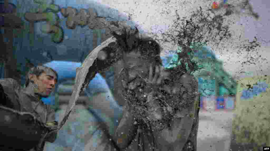 Un fêtard jette un seau de boue pendant le&nbsp;17ème festival&nbsp; de la boue sur la plage Daecheon à Boryeong, 150 km sud-ouest de Séoul, le 18 Juillet 2014.