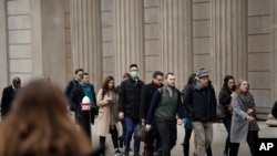 A man wearing a face mask walks past the Bank of England in London, March 4, 2020.