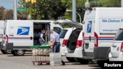 FILE - United States Postal Service workers load mail into delivery trucks outside a post office in Royal Oak, Michigan, Aug. 22, 2020. 