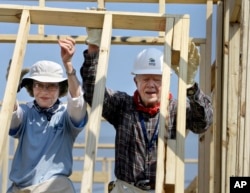 FILE - Mantan Presiden Jimmy Carter (kanan), dan mantan ibu negara Rosalynn Carter mendirikan tembok saat mereka membantu membangun rumah Habitat for Humanity di Violet, La., 21 Mei 2007. (Alex Brandon, Arsip/AP)