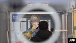 28일 서울 시청 앞 광장에 설치된 신종 코로나바이러스 임시 검사소에서 방역당국 관계자가 시민의 검체를 채취하고 있다.