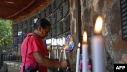 Una mujer enciende una vela en un monumento en homenaje a las víctimas de la masacre de El Mozote, en el marco de la guerra civil salvadoreña (1980-1992), el 7 de diciembre de 2019.