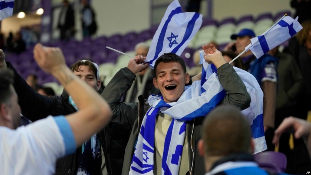 FILE - Israel supporters wave flags during the Euro 2024 qualifying playoff soccer match between Israel and Iceland, at Szusza Ferenc Stadium in Budapest, Hungary, March 21, 2024. 
