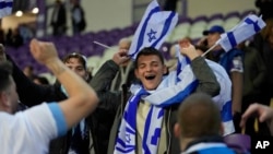 FILE - Israel supporters wave flags during the Euro 2024 qualifying playoff soccer match between Israel and Iceland, at Szusza Ferenc Stadium in Budapest, Hungary, March 21, 2024. 