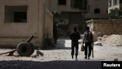 FILE - Fighters from the Free Syrian Army's Al Rahman legion walk toward their positions in Jobar, a suburb of Damascus, Syria.