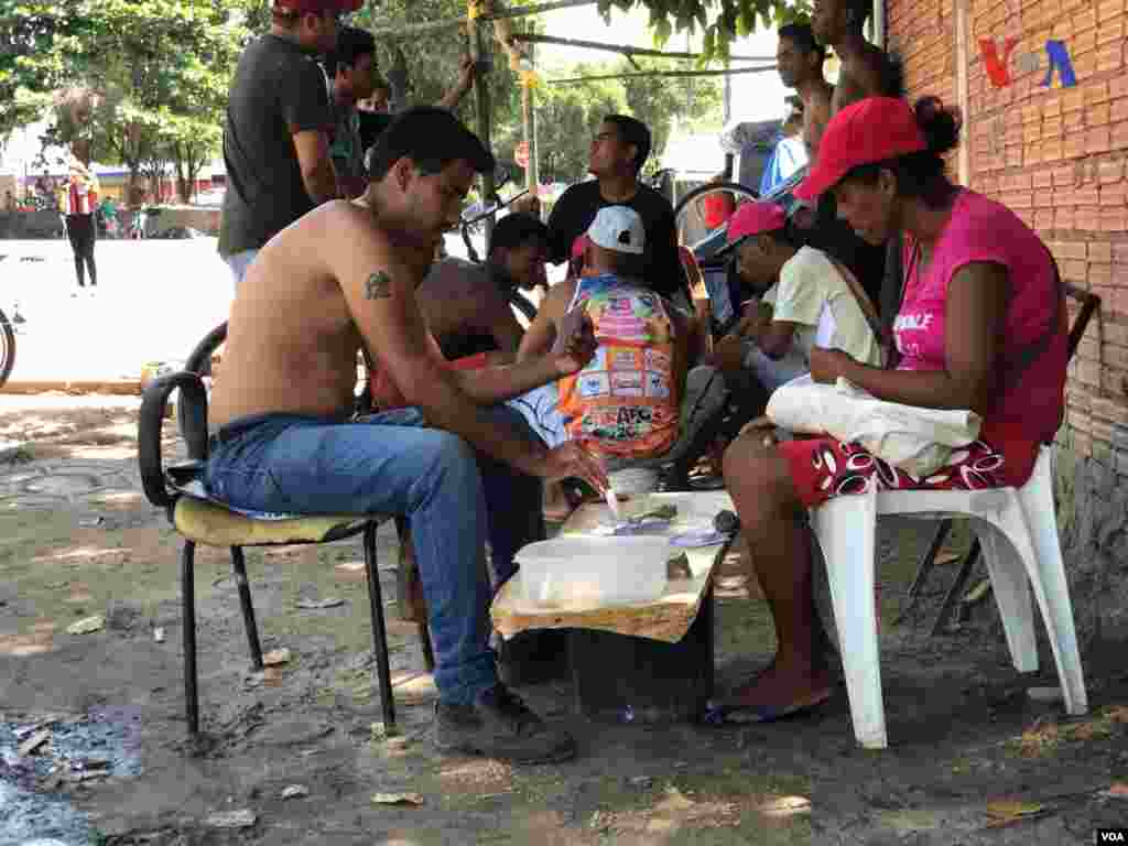 Un hombre y una mujer juegan carta en el refugio improvisado&nbsp;creado por venezolanos en el vecindario Jardim Floresta, fronterizo de Brasil. Foto: Celia Mendoza - VOA