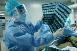 In this March 17, 2020, photo released by China's Xinhua News Agency, a medical worker looks at CT scans at the Huoshenshan field hospital in Wuhan in central China's Hubei Province.