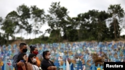 Relatives are seen during a mass burial of people who passed away due to the coronavirus disease, at the Parque Taruma cemetery in Manaus, Brazil.