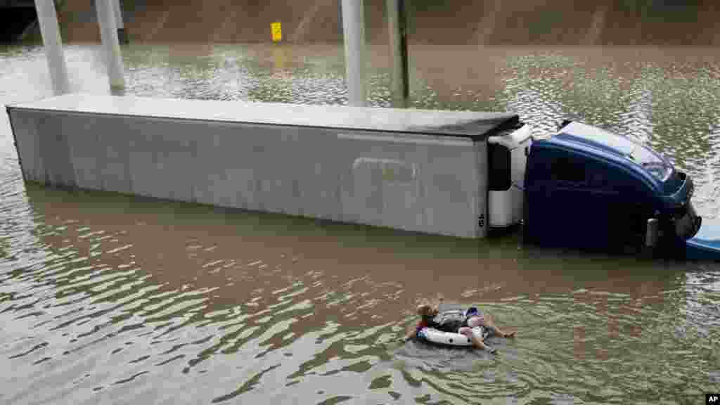 Après avoir aidé le conducteur d'un camion submergé par les eaux à sortir du véhicule, un homme flotte sur une route inondée après le passage de la tempête Harvey,&nbsp;près du centre-ville de Houston, le 27 août 2017.