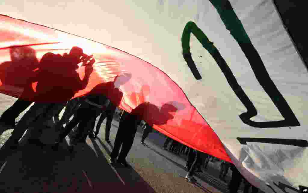 Iraqi protesters chant slogans as they wave national flags during a demonstration against corruption in Tahrir Square in Baghdad, Iraq.