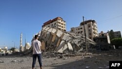 Seorang pria Palestina memperhatikan bangunan di Kota Gaza yang hancur menyusul serangkaian serangan udara ke bagian Jalur Gaza yang dikuasai oleh Hamas, Rabu, 12 Mei 2021. (Foto: Mohammed Abed/AFP)
