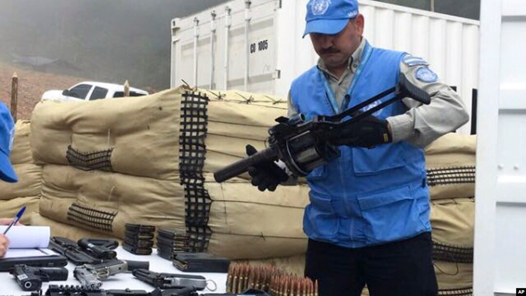 FILE - Photo released by the UN mission in Colombia shows a member of UN monitoring mission for the Colombian peace process holding a weapon handed over by rebels of the Revolutionary Armed Forces of Colombia, FARC, as part of last year's peace agreement, June 13, 2017. 