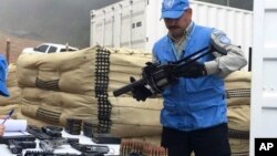 FILE - Photo released by the UN mission in Colombia shows a member of UN monitoring mission for the Colombian peace process holding a weapon handed over by rebels of the Revolutionary Armed Forces of Colombia, FARC, as part of last year's peace agreement, June 13, 2017. 