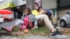 La migrante venezolana Katerine Valero, de 29 años, y sus hijos Dariusca, de 8, a la izquierda, y Wilkerson, de 4, descansan frente a un centro comercial en Bogotá, Colombia, el martes 9 de febrero de 2021.