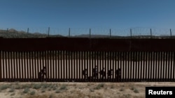 Una vista de un dron muestra a migrantes solicitantes de asilo mientras caminan a lo largo del muro fronterizo tras cruzar la frontera hacia los EEUU, en Jacumba Hot Springs, California, visto desde México, el 16 de mayo de 2024.