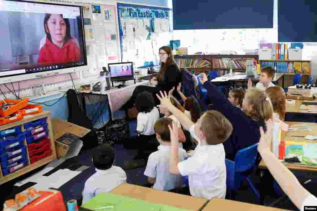 Students at the Holne Chase School interact with a class member via the internet as his family self-isolates amid the coronavirus pandemic, in Milton Keynes, Britain.