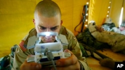 FILE - Pfc. Ralph Abbatiello of Long Island, New York, plays one of the latest versions of Pokemon while awaiting deployment at a camp in Kuwait, April 3, 2003.