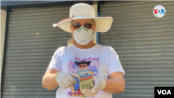 Una mujer con mascarilla para protegerse del COVID-19 cambia remesas en un punto transitado de Managua. [Foto Houston Castillo, VOA]