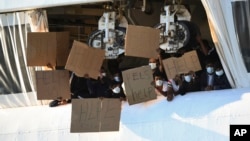 FILE - Migrants hold banners asking for help, from a deck of the Norway-flagged Geo Barents ship operated by Doctors Without Borders, in Catania's port, Sicily, southern Italy, Oct. 7, 2022.