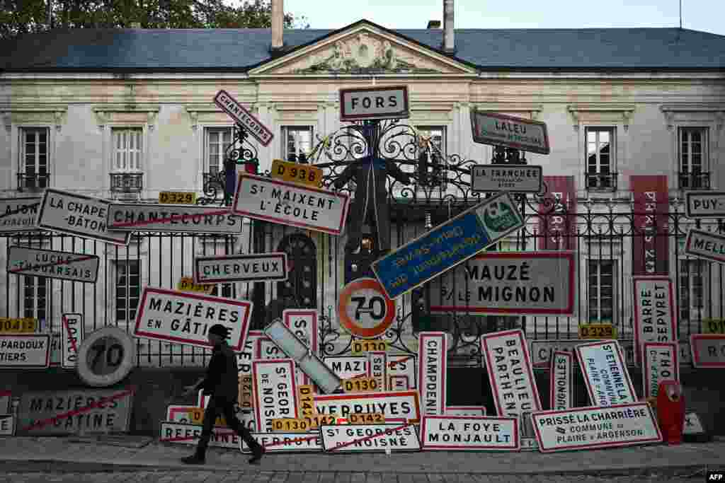 A worker adjusts his glove before removing road signs left by French farmers overnight on the gate of the Deux Sevres' prefecture in Niort, southwestern France, Nov. 8, 2024.