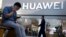 Sử dụng điện thoại thông minh bên ngoài một cửa hiệu Huawei ở Bắc Kinh, 20 tháng Năm, 2019. Hình minh họa.