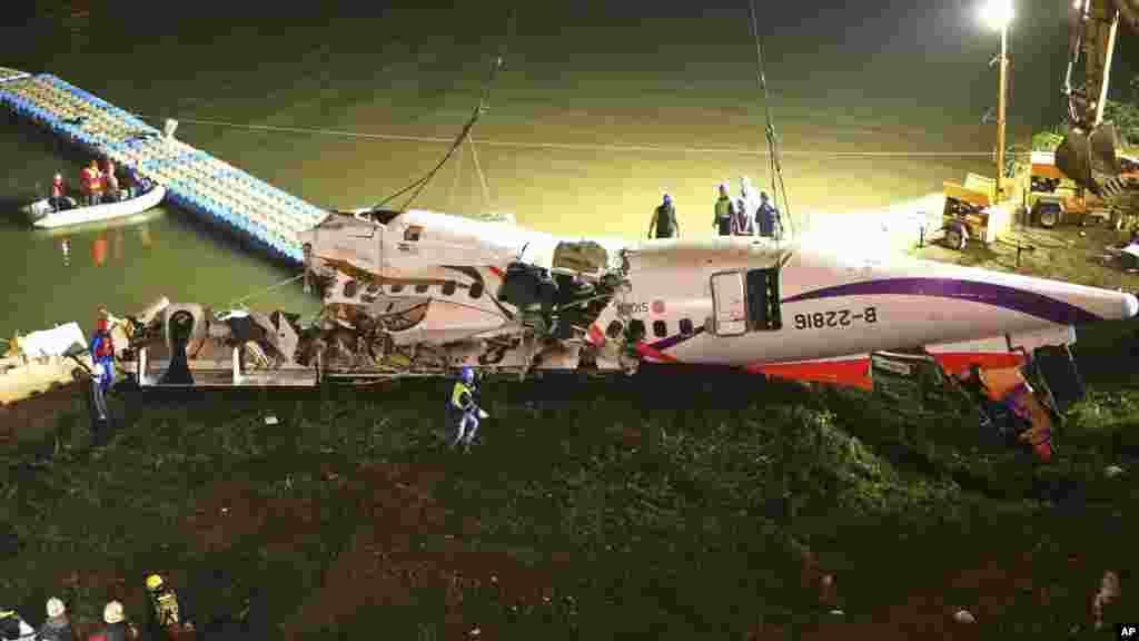 The mangled fuselage of a TransAsia Airways commercial plane is dragged to the river bank after it crashed in Taipei, Taiwan.