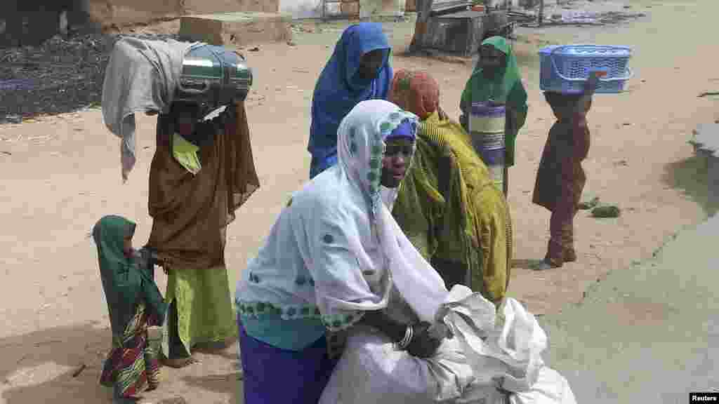 A woman with her children pack what is left of their belongings, following an attack in Kawuri January 28, 2014.