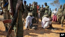 FILE - Alleged members of al-Shabab are blindfolded and guarded at a former police station by soldiers of the Somali National Army, in Kismayo, southern Somalia. 
