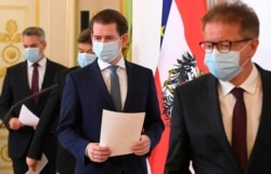 FILE - Austrian ministers arrive for a news conference about the coronavirus situation in Austria, in Vienna, Austria, April 6, 2020.