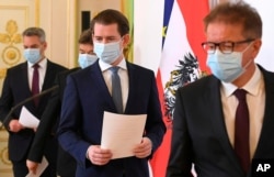 FILE - Austrian ministers arrive for a news conference about the coronavirus situation in Austria, in Vienna, Austria, April 6, 2020.
