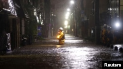 FILE - Firefighters patrol a road flooded by heavy rains from Typhoon Hagibis at Ota ward in Tokyo, Japan, Oct. 12, 2019, in this photo taken by Kyodo.