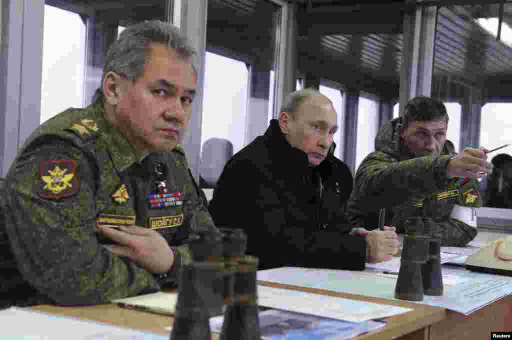 Presiden Rusia Vladimir Putin (tengah), Menteri Pertahanan Sergei Shoigu (kiri) dan kepala departemen persiapan tempur militer Rusia Ivan Buvaltsev, menyaksikan latihan militer di tempat menembak Kirillovsky di Leningrad (3/3). (Reuters/Mikhail Klimentyev)