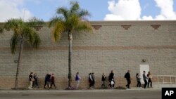 Volunteers carry donated items towards a group of undocumented migrants looking for work as day laborers alongside a hardware store in San Diego, California, Feb. 4, 2017.