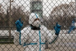 FILE - A medical staffer wearing a protective suit waits at a triage check point that was set to ease the pressure on hospital emergency wards, following the surge of COVID-19 case numbers, at the Monza racetrack, in Monza, Italy, Nov. 11, 2020.