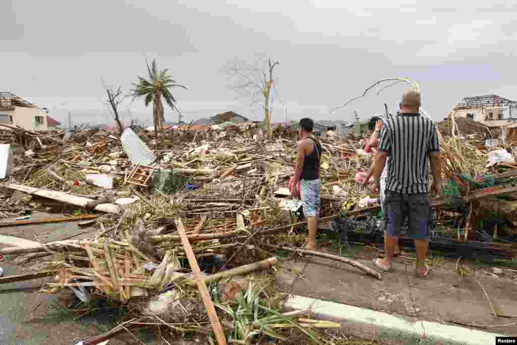 Para penyintas memeriksa kerusakan akibat Topan Haiyan menghantam kota Tacloban, Filipina Tengah (9/11).