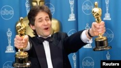 James Horner holds up two Oscars after winning for Best Original Song and Original Dramatic Score for his work on the movie "Titanic," at the 70th Annual Academy Awards, March 23, 1998.