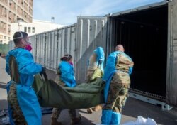 In this Jan. 12, 2021 National Guard members are assisting with processing COVID-19 deaths, placing them into temporary storage at the medical examiner-coroner's office in Los Angeles.