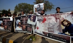 FILE - Supporters of Naqeebullah Mehsud, who was killed by police, hold a banner that reads "The People of Karachi Demand the Arrest of the Killers of Naqeebullah Mehsud and take the Logical End," in Karachi, Pakistan, Jan. 27, 2018.