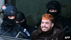 French convict and drug trafficker Mohamed Amra (R) is escorted by policemen out of the Court of Appeal in Bucharest on Feb. 23, 2025, after a hearing one day after his arrest under European arrest warrant. 